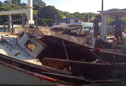 Puerto rican fishing family observers the burned ruins of their boat 